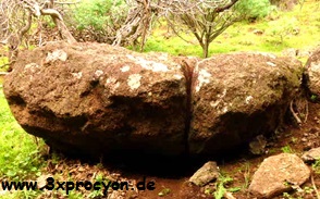 Ein teilweise unterhöhlter Felsbrocken mit einer breiten Spalte im Hang.